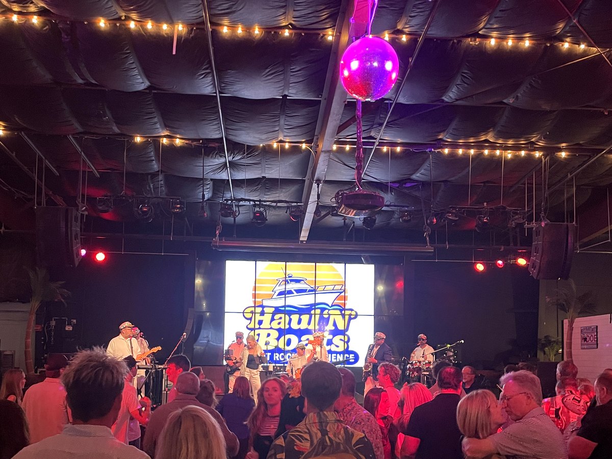 Crowd dancing in front of the Haul 'N Boats sunset backdrop