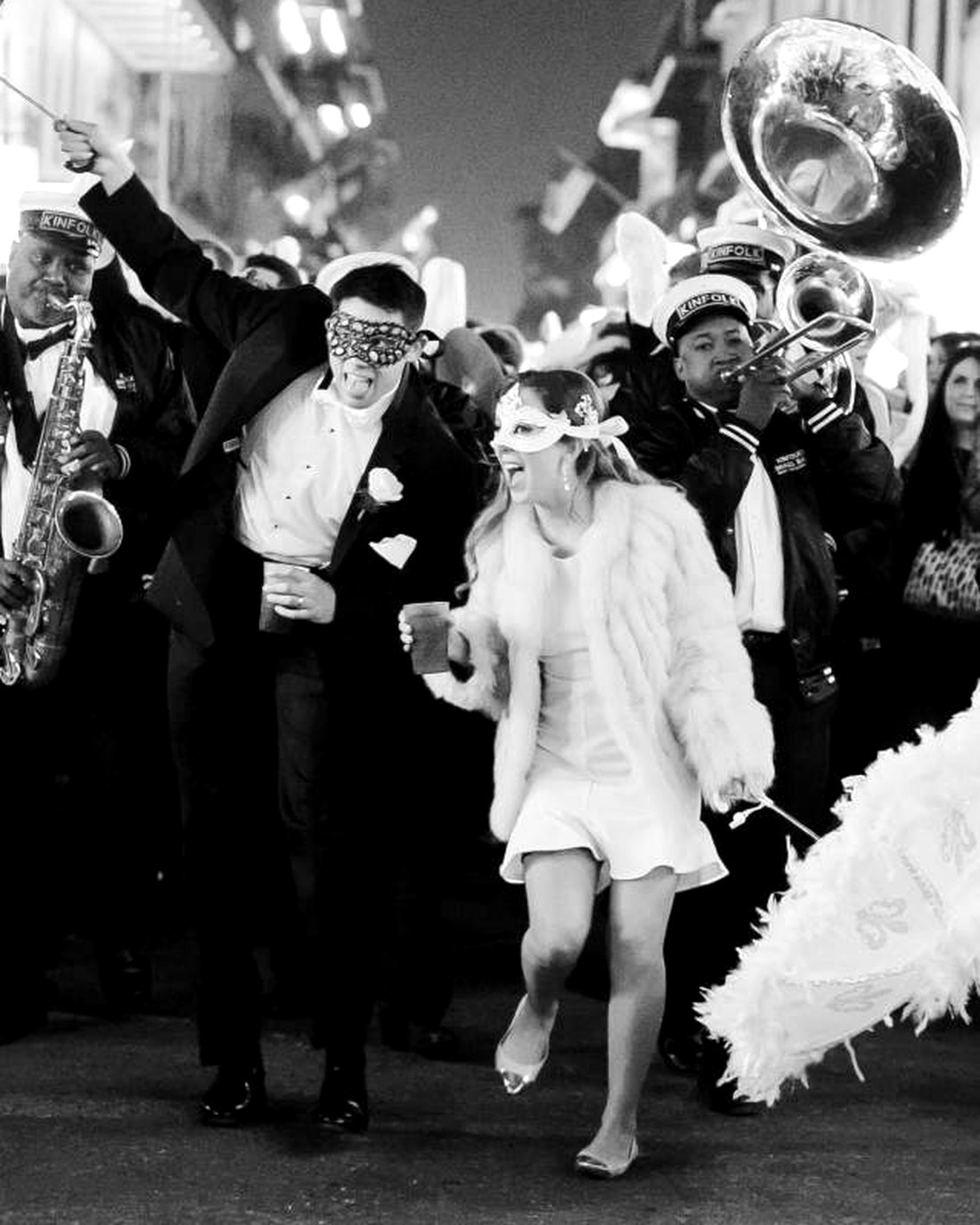 Bride and groom leading a second line parade with a brass band through the French Quarter